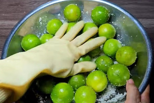 Bàn tay đang chà xát chanh với muối hạt để loại bỏ tinh dầu và làm sạch chanh muối