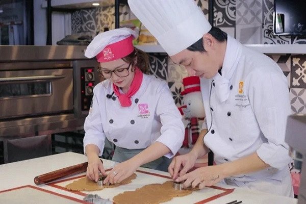 Bàn tay đang tạo hình bánh cookies Noel với khuôn cây thông và người tuyết.