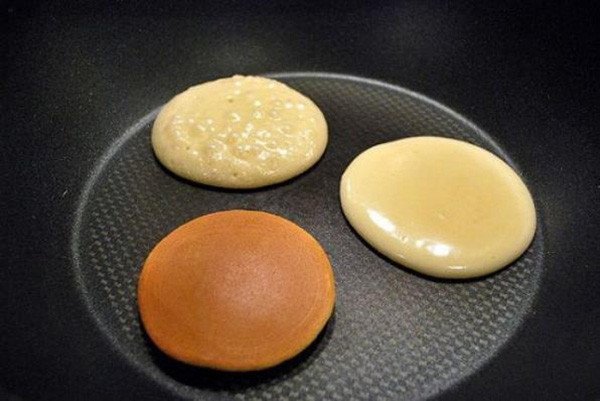 Bánh rán Doremon đang được rán trên chảo chống dính, màu vàng đều