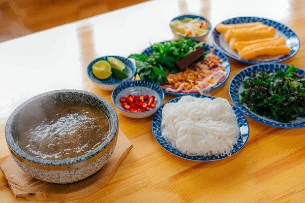 Bát phở dê nóng hổi nghi ngút khói trong bát đá, với thịt dê thái lát, rau thơm và nước dùng trong vắt.