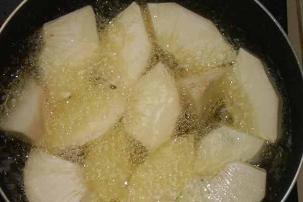 Chảo dầu nóng đang chiên những lát sake vàng đều