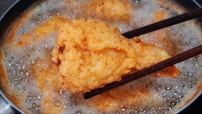 Chiên gà trong chảo dầu sôi ở nhiệt độ lý tưởng để có lớp vỏ giòn rụm.