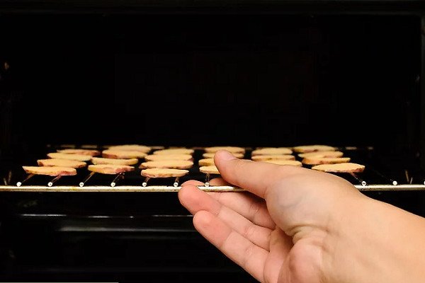 Cho khay chuối đã chuẩn bị vào lò để bắt đầu quá trình sấy khô