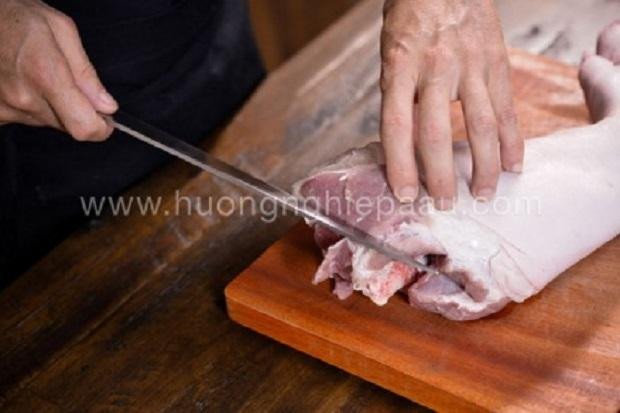 Đặt chân giò heo đã làm sạch lên thớt để bắt đầu quy trình rút xương.