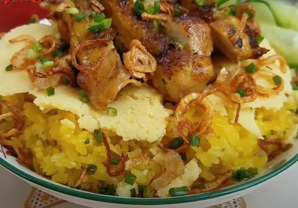 Đĩa xôi gà xá xíu với thịt gà đỏ au, bóng bẩy, được thái lát mỏng và xếp gọn gàng trên xôi, kèm chút dưa góp