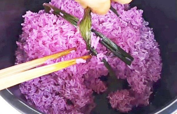 Đĩa xôi màu tím đang được xới đều và thêm gia vị trong quá trình đồ
