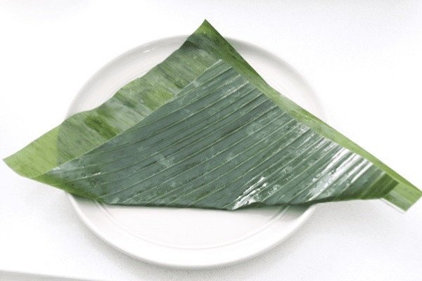Gấp lá chuối thành hình tam giác để bắt đầu gói bánh giò truyền thống