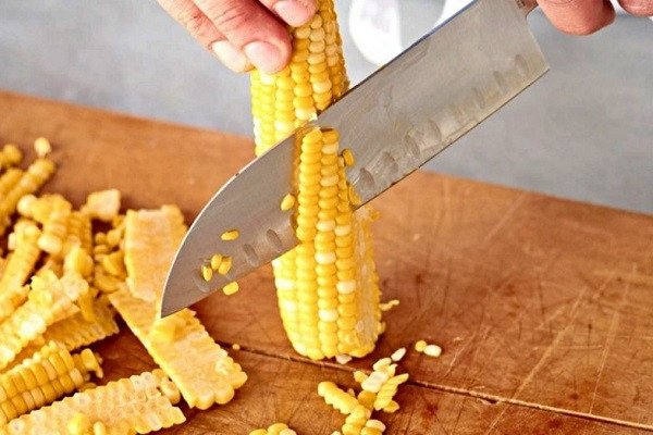 Hình ảnh mô tả cách tách hạt ngô ngọt từ cùi để làm bánh ngô chiên