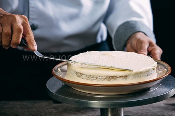Hình ảnh phủ kem phô mai (cream cheese) lên bánh cà rốt, tạo bề mặt mịn màng