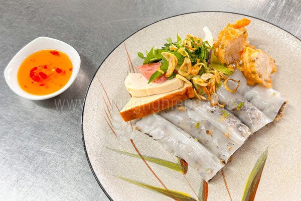 Khay bánh cuốn với nhiều loại topping hấp dẫn như chả lụa, nem chua, và rau thơm