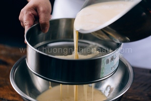 Lọc hỗn hợp trứng sữa và nước cốt lá dứa qua rây để đảm bảo bánh Flan lá dứa mịn màng