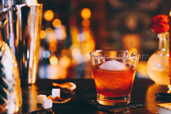 Ly cocktail Old Fashioned cổ điển với đá lớn, trang trí vỏ cam và cherry, biểu tượng của sự pha chế tinh tế