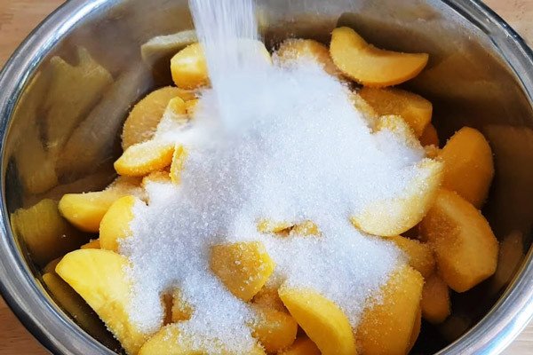 Miếng đào tươi được trộn đều với đường, chuẩn bị cho quá trình ướp đào ngâm
