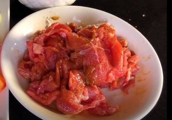 Miếng thịt bò thái lát mỏng đang được ướp với bột năng và gia vị, bí quyết giúp thịt bò mềm ngọt và không bị dai khi chế biến món nui xào bò.