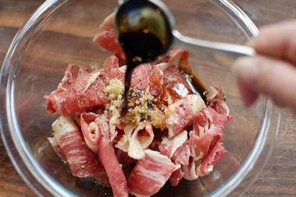 Miếng thịt bò tươi ngon đã thái lát mỏng, chuẩn bị ướp gia vị cho món nui xào bò