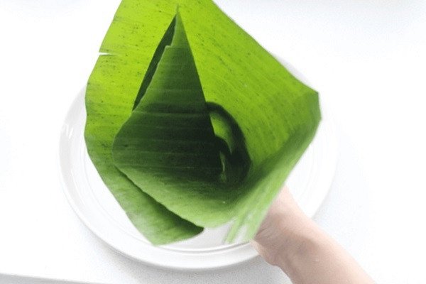 Mở lá chuối tạo hình phễu kín đáo để đổ bột làm bánh giò