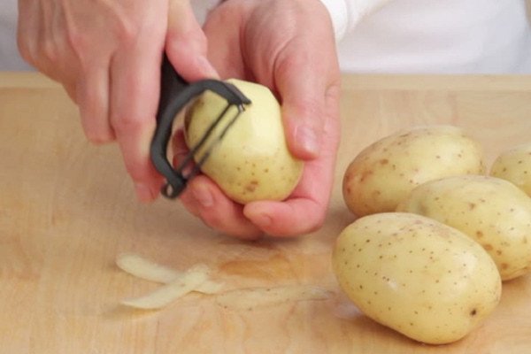 Mô tả hình ảnh người đang gọt vỏ khoai tây để chuẩn bị làm khoai tây lắc phô mai