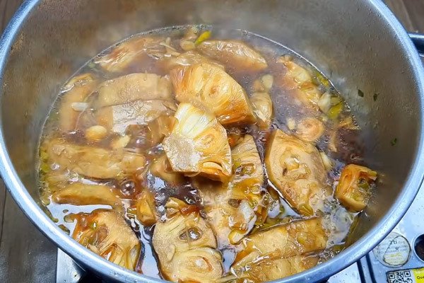 Món mít non kho chay đang được nấu, nước sốt dừa sánh đặc