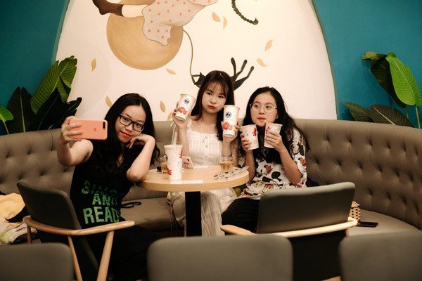 Một nhóm khách hàng trẻ đang thưởng thức trà sữa trong không gian quán được trang trí đẹp mắt, minh họa chi phí vận hành và marketing