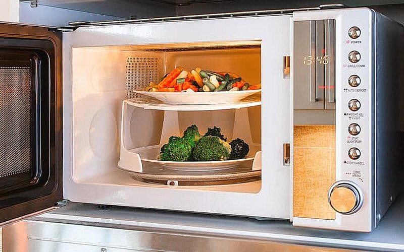 Một tô canh hoặc món ăn được hâm nóng nhanh chóng bằng lò vi sóng, tiện lợi cho bữa ăn.