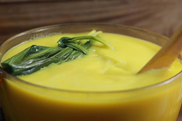 Người đang khuấy đều hỗn hợp sữa bí đỏ trên bếp để đảm bảo độ sánh mịn và không bị cháy