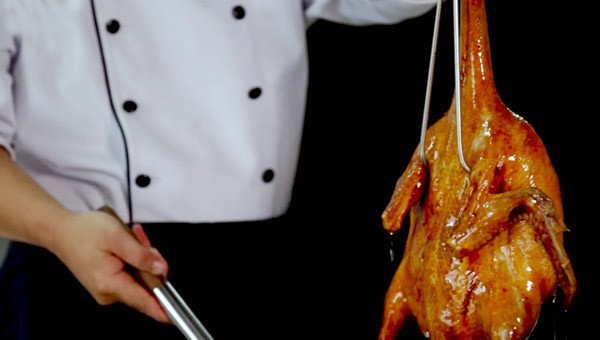 Người đầu bếp đang khéo léo xối dầu nóng lên toàn bộ thân vịt quay, giúp lớp da trở nên vàng óng, căng bóng và giòn rụm hoàn hảo.