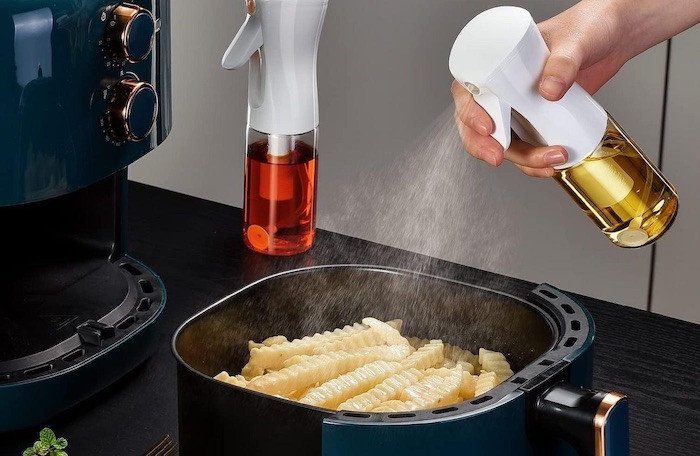 Người dùng đang xịt dầu ăn chống dính lên bề mặt thực phẩm trước khi cho vào nồi chiên không dầu