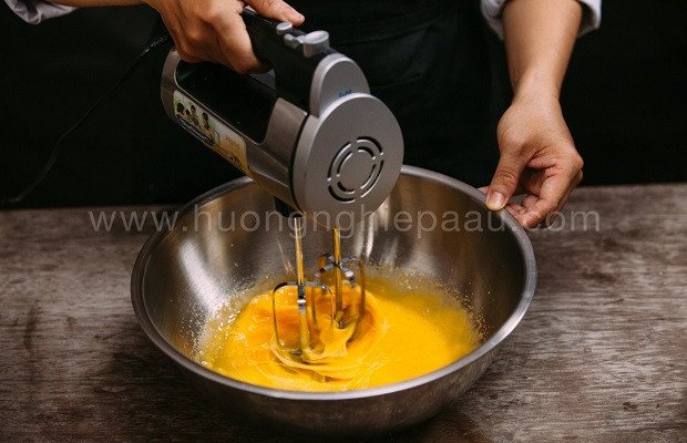 Người làm bánh đang đánh bông lòng đỏ trứng gà cùng vani và đường, chuẩn bị cho phần cốt bánh bông lan trà xanh cuộn kem tươi mềm mịn