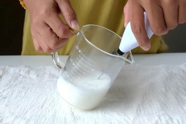 Người pha chế đang dùng máy đánh bọt sữa tươi cho món cacao đá