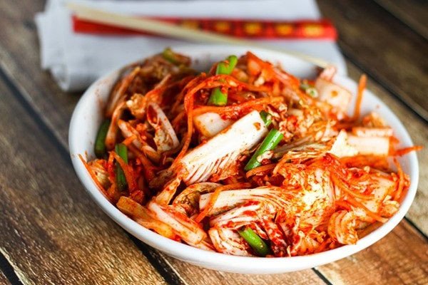 Người phụ nữ đang cẩn thận thoa sốt gia vị vào từng bẹ cải thảo để làm kim chi tại nhà