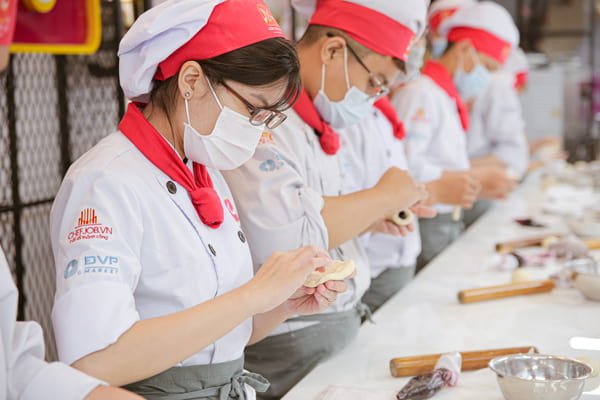 Người thợ làm bánh đang trang trí chiếc bánh ngọt tinh xảo với kem tươi và trái cây.