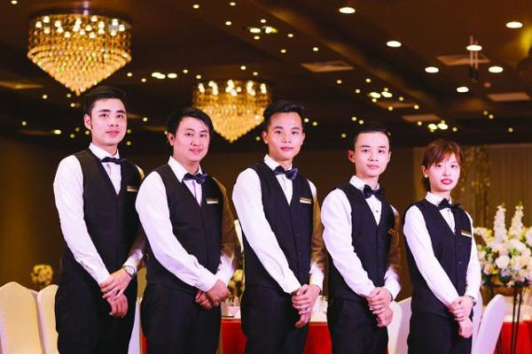 Nhân viên casual phục vụ bàn tiệc với đầy đủ ly tách