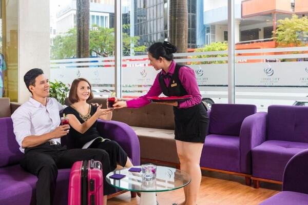 Nhân viên lễ tân niềm nở chào đón khách, thể hiện tinh thần hospitality chuyên nghiệp trong ngành dịch vụ.