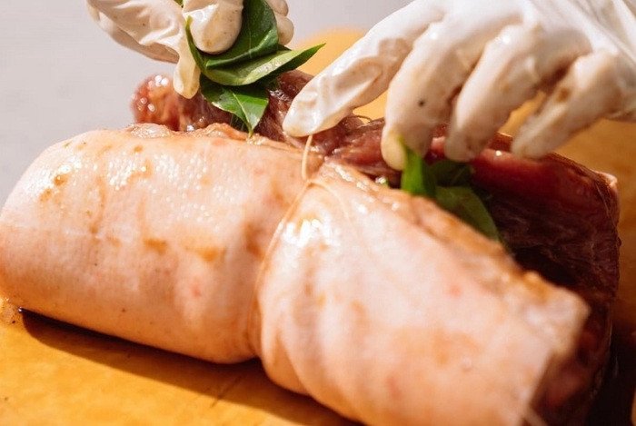 Nhồi lá mắc mật vào giữa miếng thịt heo và buộc/khâu lại để giữ hương vị