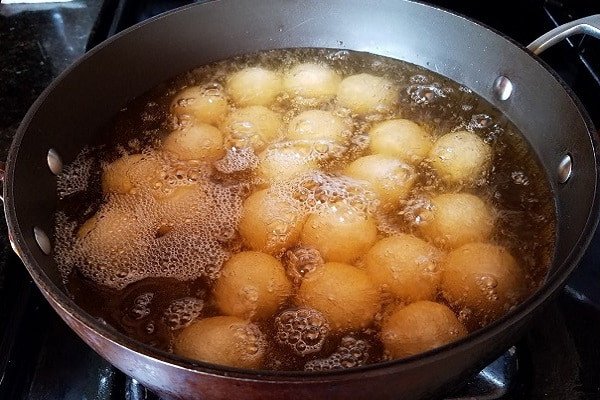Những chiếc bánh rán ngọt đang được chiên vàng giòn trong chảo dầu.