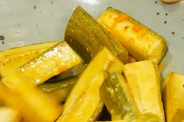 Những miếng chuối xanh đang được ướp đều với nghệ và mẻ, tạo màu vàng đẹp mắt cho món ốc chuối đậu.