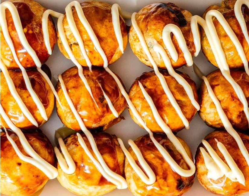 Những viên bánh Takoyaki vàng ruộm đang được nướng trong lòng nồi chiên không dầu, giảm thiểu dầu mỡ