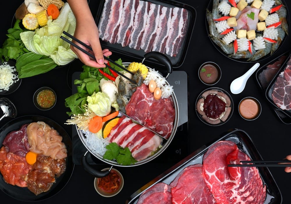 Nồi lẩu gầu bò Mỹ đang sôi sùng sục, xung quanh là đĩa thịt gầu thái lát và rau sống