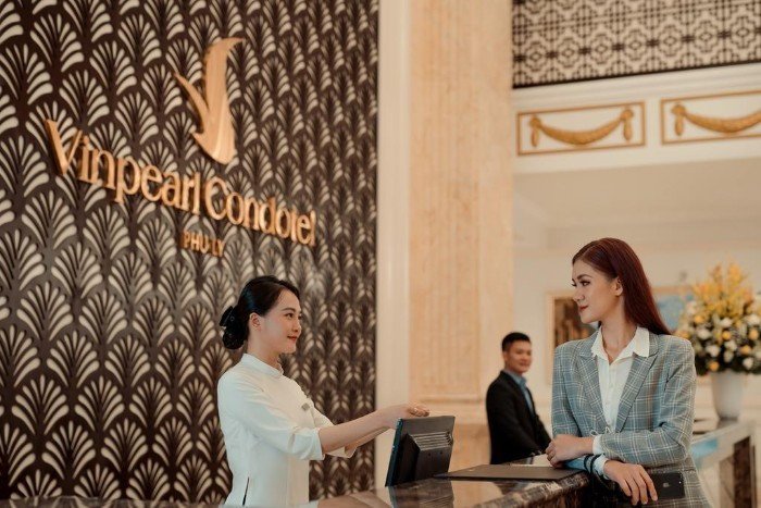 Nữ lễ tân chuyên nghiệp tại quầy tiếp tân, biểu tượng ca làm việc linh hoạt trong khách sạn