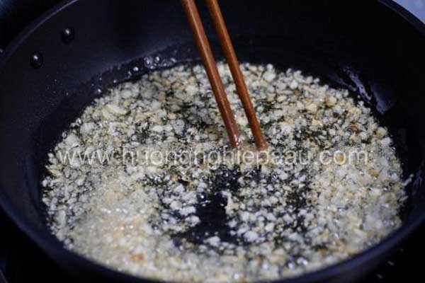 Phi thơm tỏi trong chảo để chuẩn bị xào măng và ốc