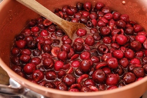 Quá trình nấu mứt cherry đang sôi sệt trên bếp