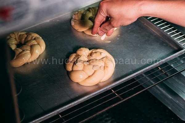 Quét trứng và rắc hạnh nhân lên bánh mì hoa cúc trước khi nướng
