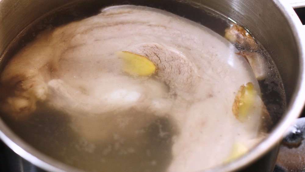 Sơ chế và luộc thịt ba chỉ để chuẩn bị làm món thịt heo quay.