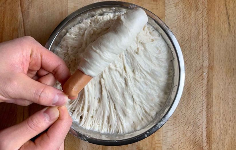 Tạo hình bánh hotdog bằng cách nhúng xiên xúc xích phô mai vào tô bột bánh mì.