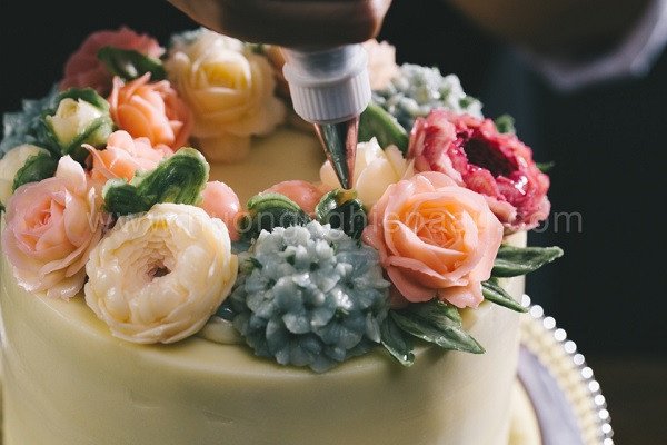 Thợ bánh kem đang thực hiện kỹ thuật bắt bông kem bơ tỉ mỉ.