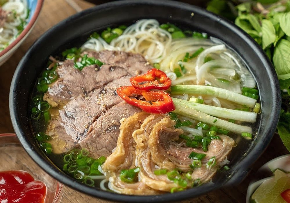 Tô phở nạm bò nóng hổi với nước dùng trong vắt, thịt nạm thái mỏng, rau thơm xanh tươi