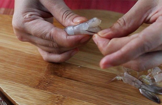 Tôm tươi đang được loại bỏ chỉ đen trên lưng bằng dao nhọn