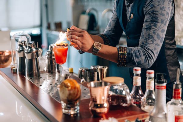 Vỏ cam đang được đốt cháy nhẹ để giải phóng tinh dầu thơm, kỹ thuật tạo hương vị đặc biệt cho ly cocktail