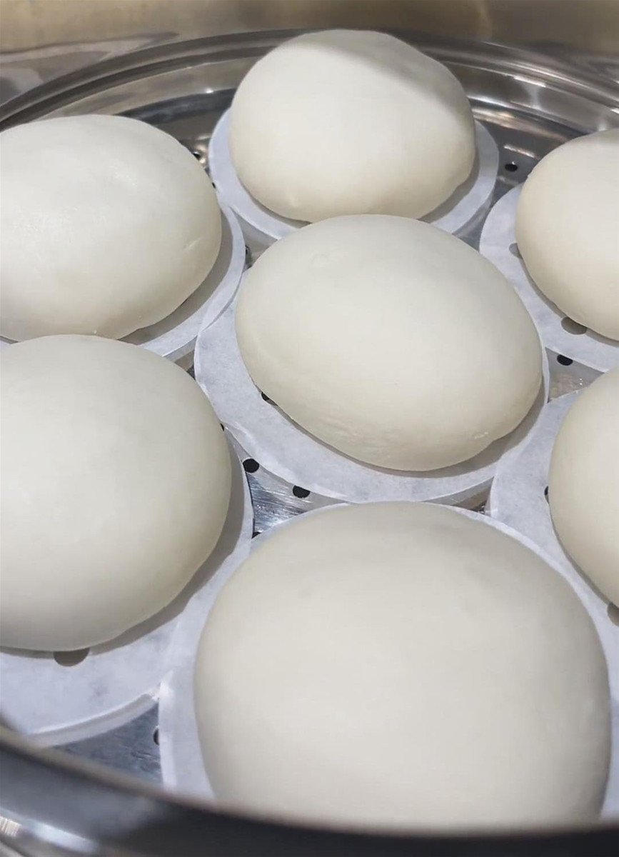 Xếp bánh bao vào khay nồi chiên không dầu có lót giấy nến, đảm bảo khoảng cách đều để hấp chín