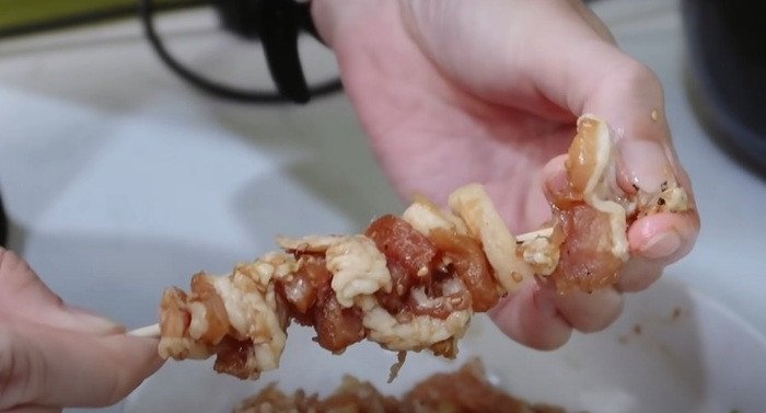 Xiên thịt heo vào que xiên một cách đều đặn, đảm bảo không quá chặt để thịt chín đều khi nướng